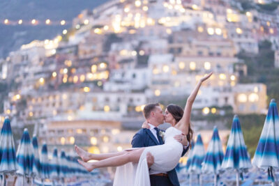 The groom hold th ebride without her shoes for photo in front of the hill by sunset