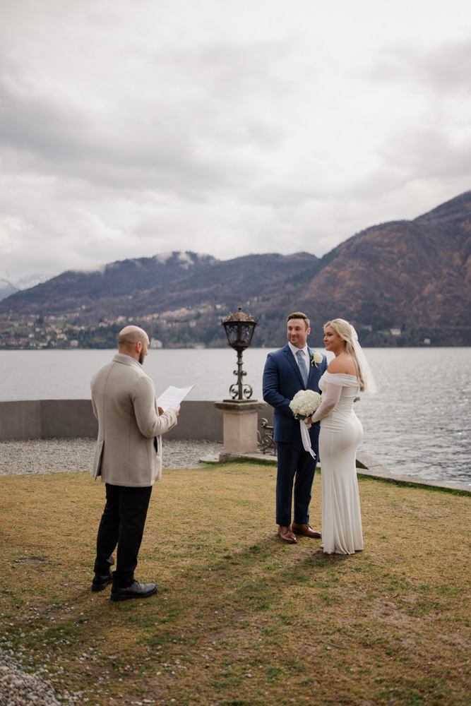 The celebrant reading the text of the elopement facing the couple with lake as a backdrop