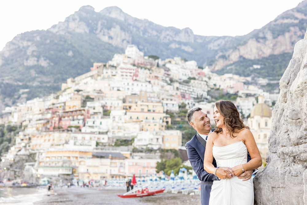 The couple during the photo shoot on the beach with the Positano village in the backgrounbd