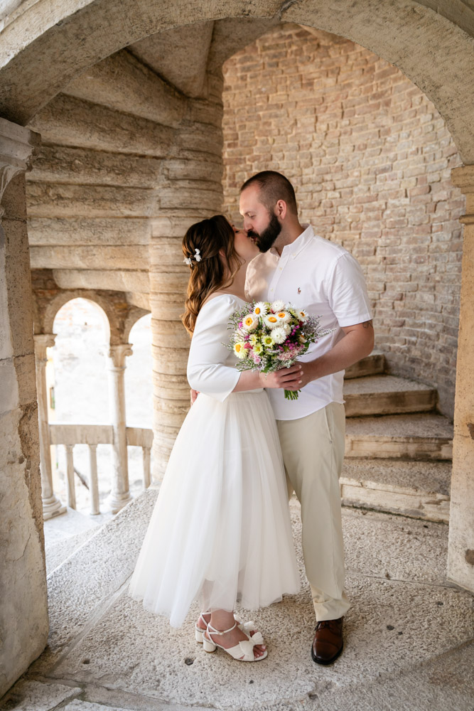 The couple kiss at Scala Contarini del Bovolo after their ceremony