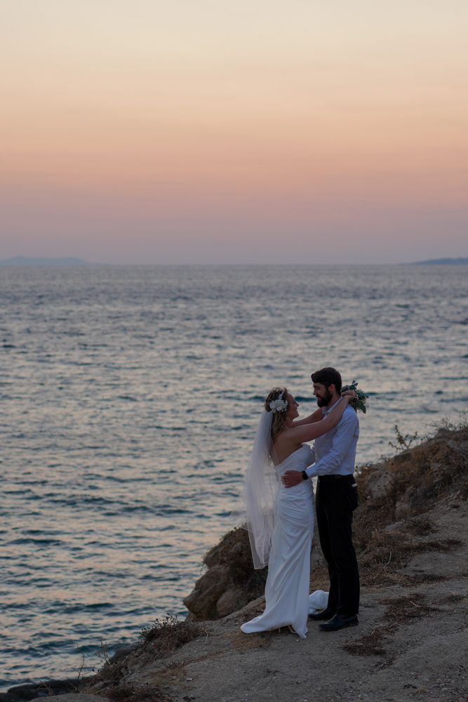 The couple over the see in Mykonos at sunset after the ceremony of Elopement