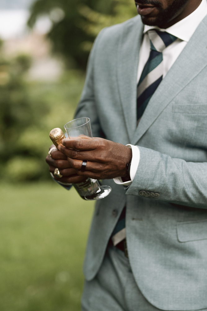 One of the groom opens a bottle of champagne