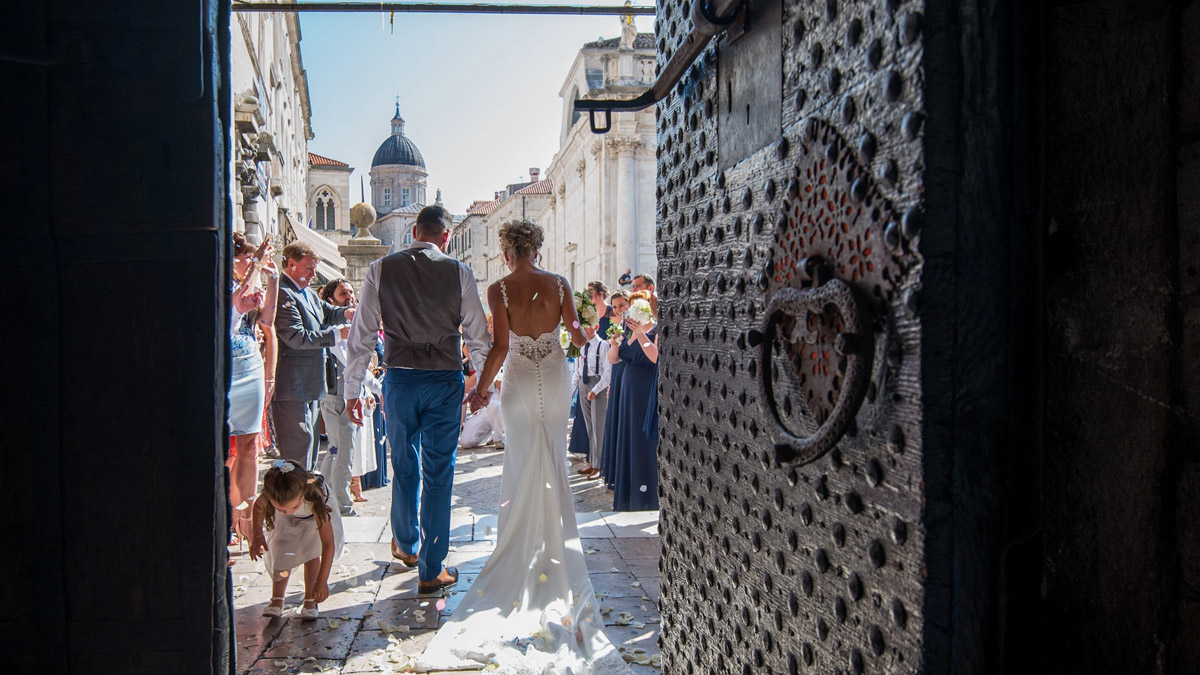 The coupke walking to the exit of the church after their wedding, a photo from their back to see the guests