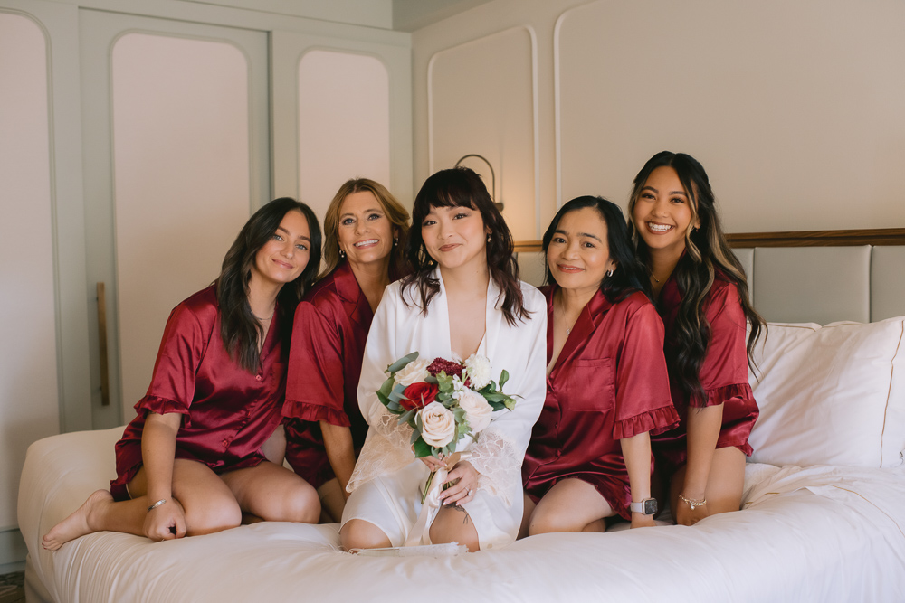 The bridesmaids around the bride on the bed for a funny moment during getting ready