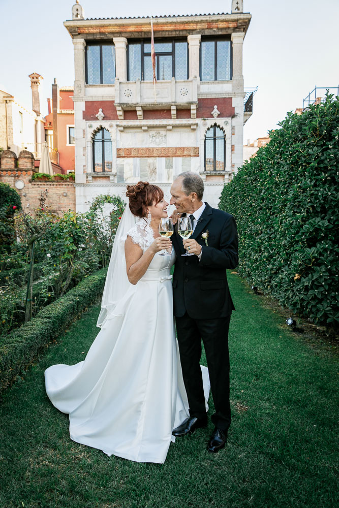 The couple drink a glass after their ceremony in the rose garden in Venice