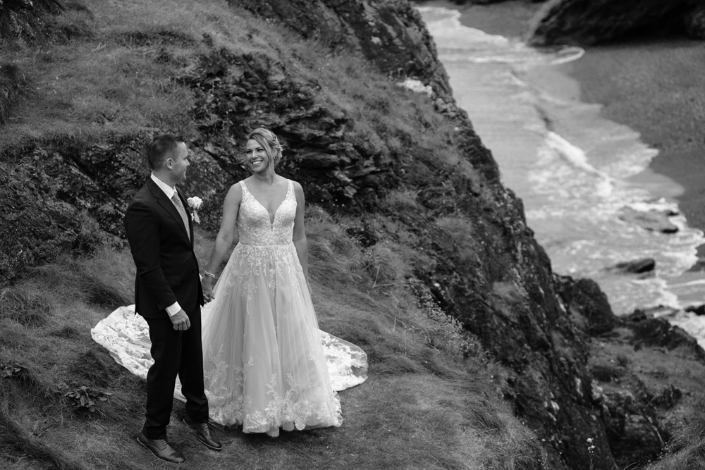 bride and groom posing above the beach at Black Castle