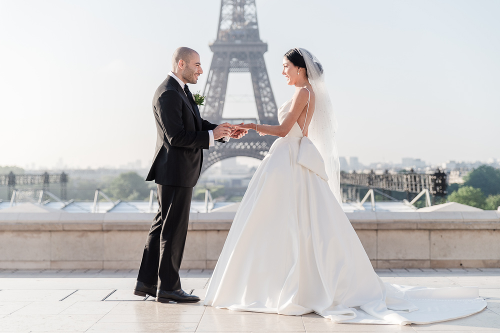 The groom slides the ring to th ebride