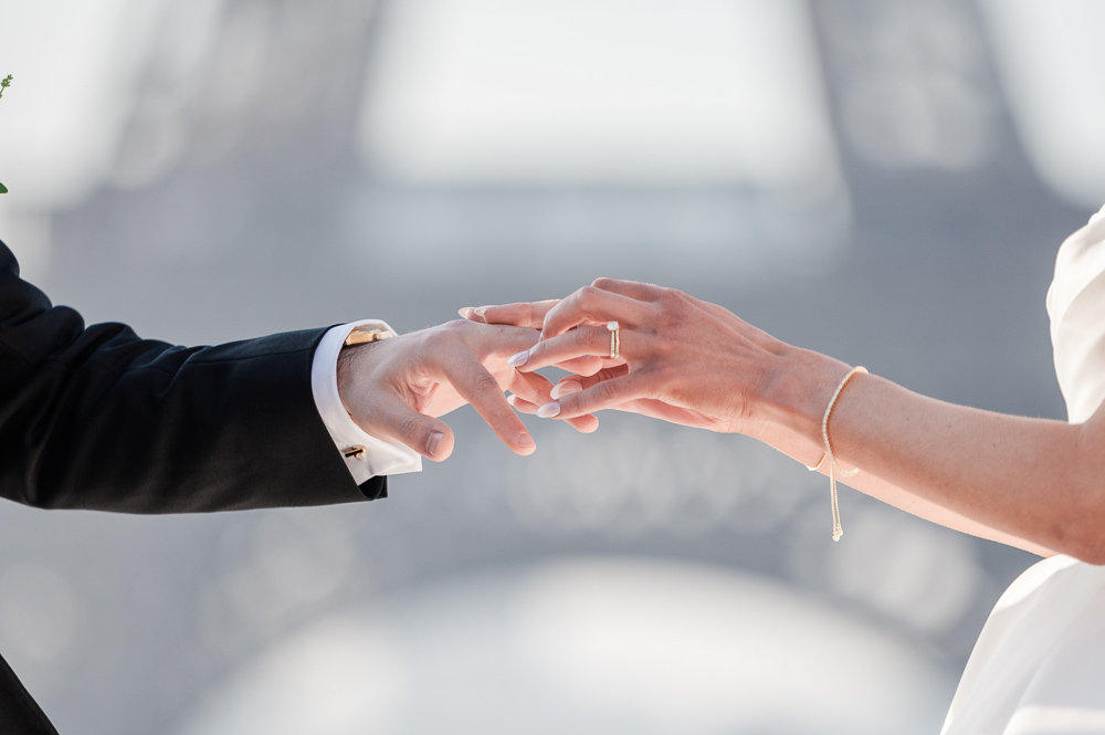 The 2 hands of the couple with the Eiffel as whitness in the background