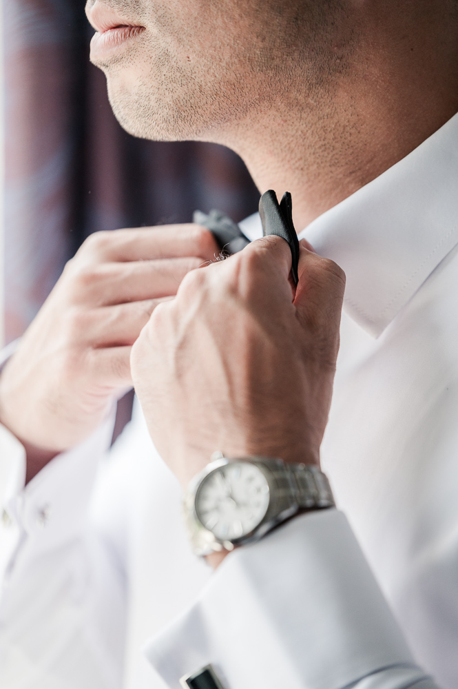 The groom finishing his bow tie knot