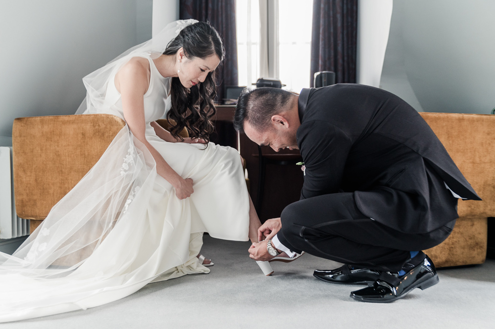 a funny moment when the groom help the bride to get ready with her shoes