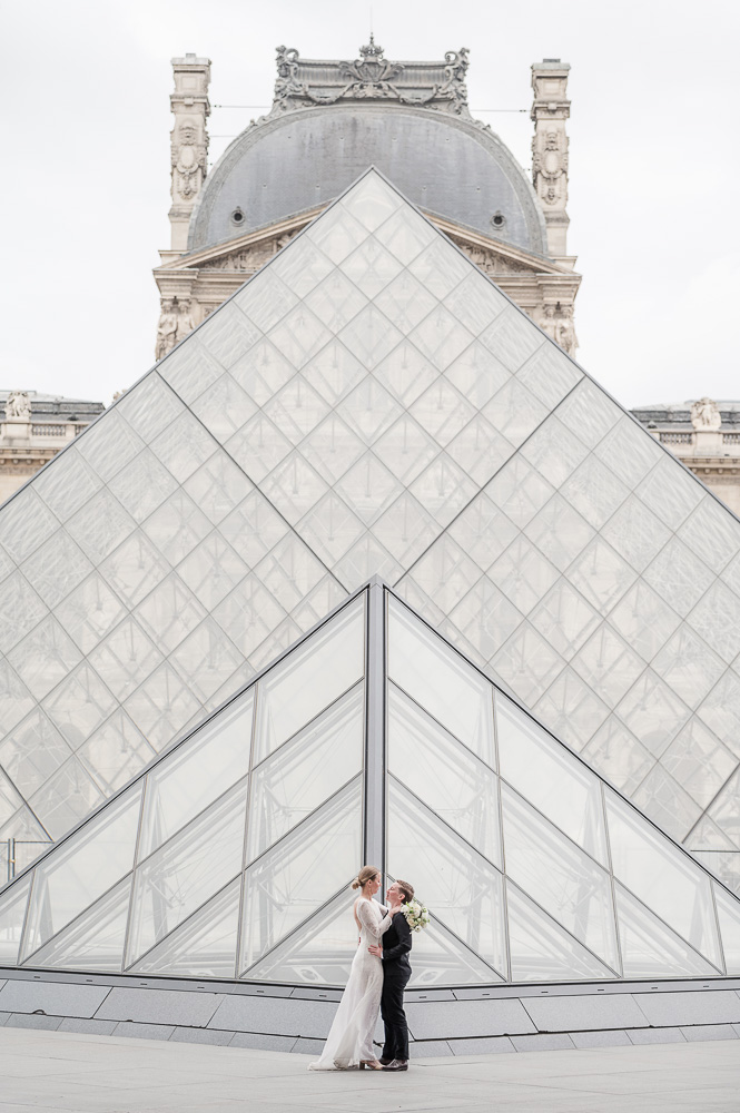 The 2 brides alone at Louvre courtyard, posing in front of the Pyramid