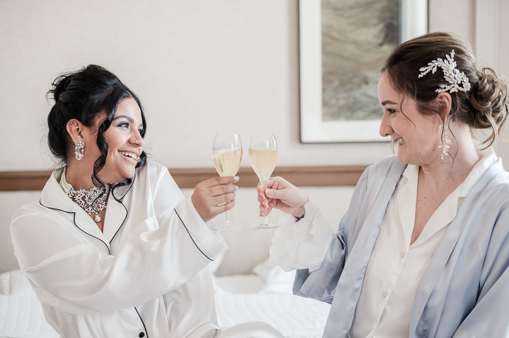 The 2 brides enjoying the moment on their bed and siruping a glass of champagne