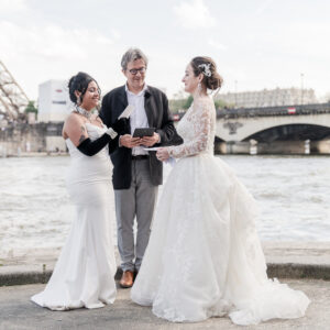 The 2 brides by the river during the ceremony in front of Eiffel tower