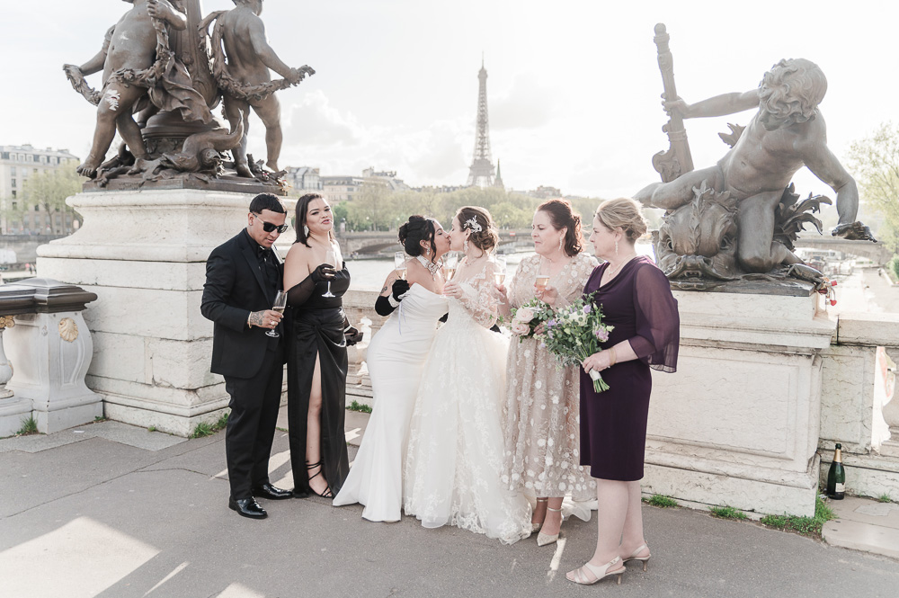 the brides kissing surrounded by their families