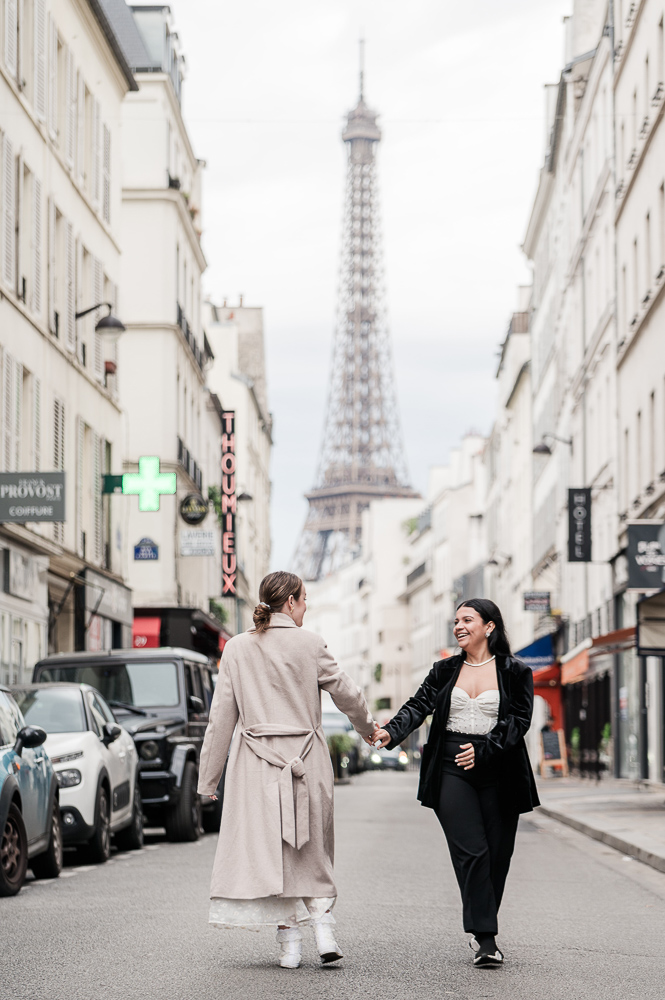 walking in the street hand to hand, the 2 brides are in paris with Eiffel in the background