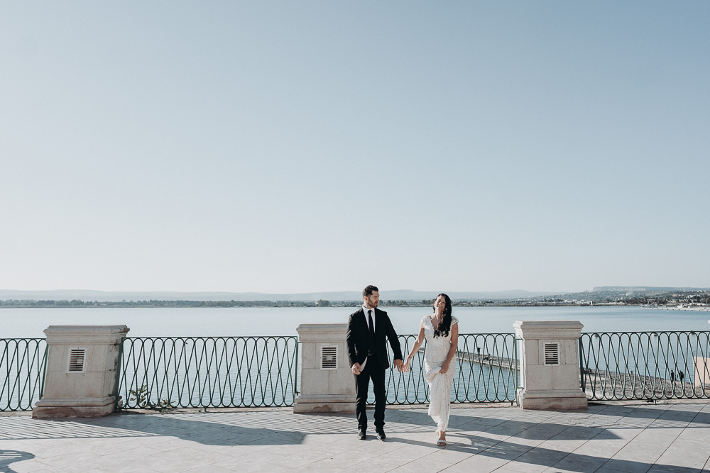 The beautiful view over the see for an elopement in Syracuse, the couple takes the time to walk hand to hand