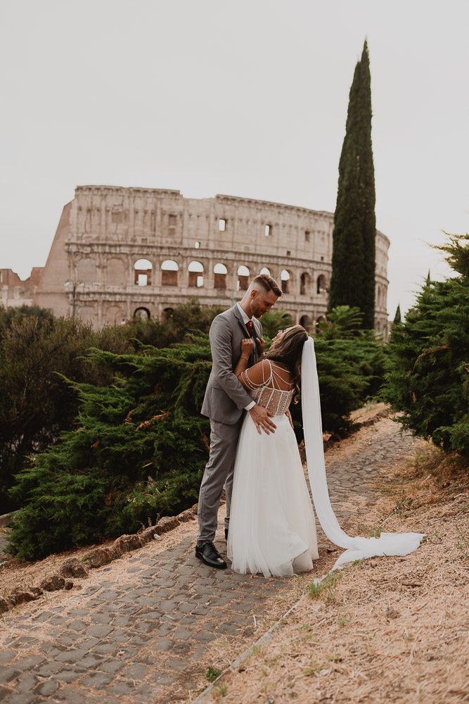 Sunset elopement in Rome with a happy couple posing in front of the Colosseum