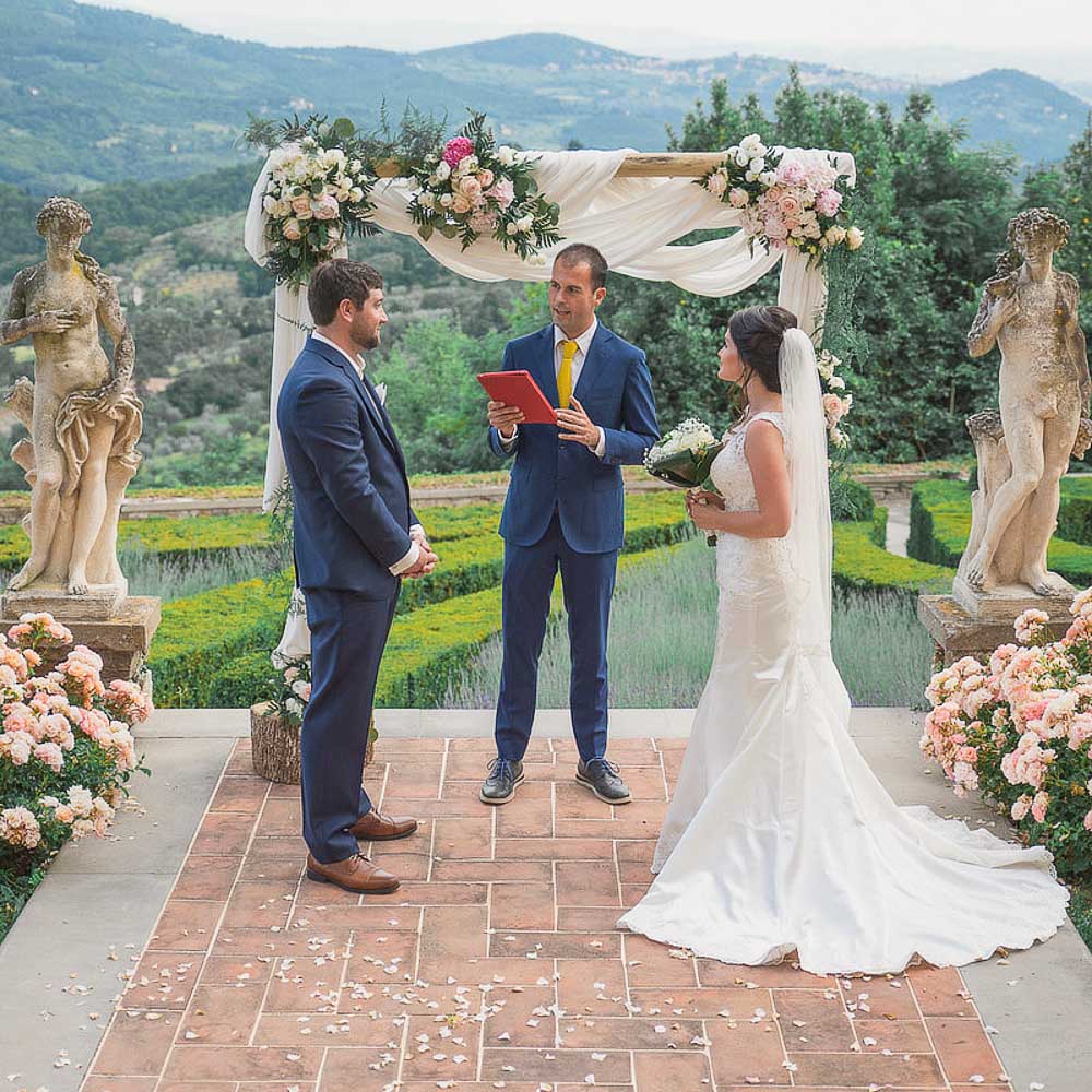 The celebrant in front of the flowers arch and starting to tell the story of the couple